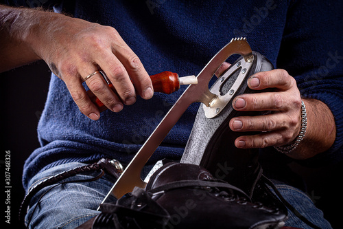 Photos Man's hand and handheld skate sharpening tool with ice skate