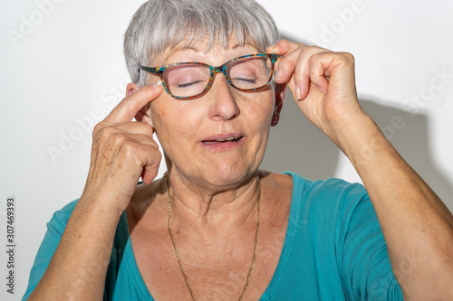 caucasian senior woman with glasses scratching her eye on isolated White background photo