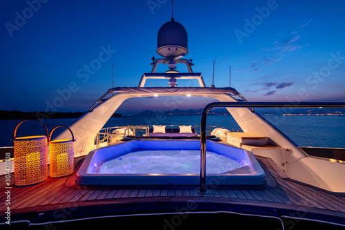 Luxury yacht with lights and a jacuzzi sailing in the sea at night