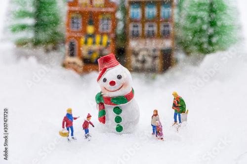 Happy snowman on snow with background of blurred Christmas pine. Miniature people in Christmas Theme.