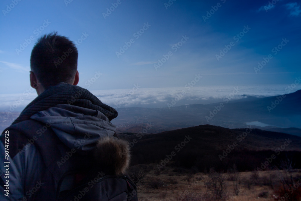 Tourist, traveler standing on background view mockup. Young man with backpack traveling n the mountains