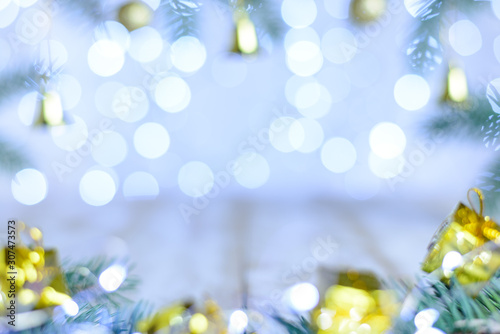 Christmas blurred background with bokeh circles. Golden decoration with pine branches. Copy space, selective focus.