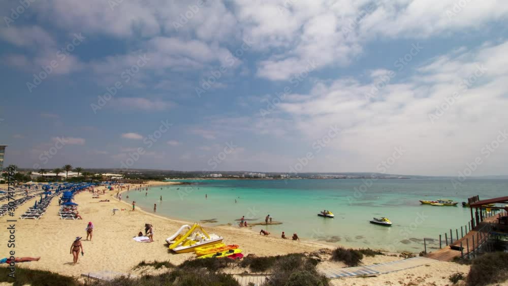 Cyprus Ayia Napa city. Macronissos beach. A row of blue beach umbrellas, white sand and turquoise sea water. Timelapse