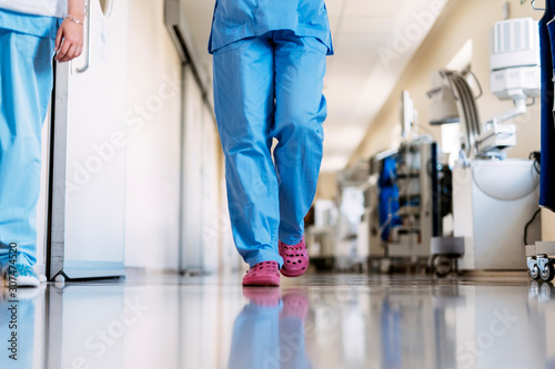 Unrecognizable nurse walking through hospital hallway photo