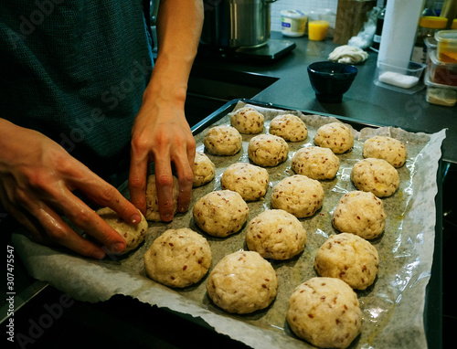 Preparing raw keto dough for baking gluten-free buns, laying in a row on a baking sheet 