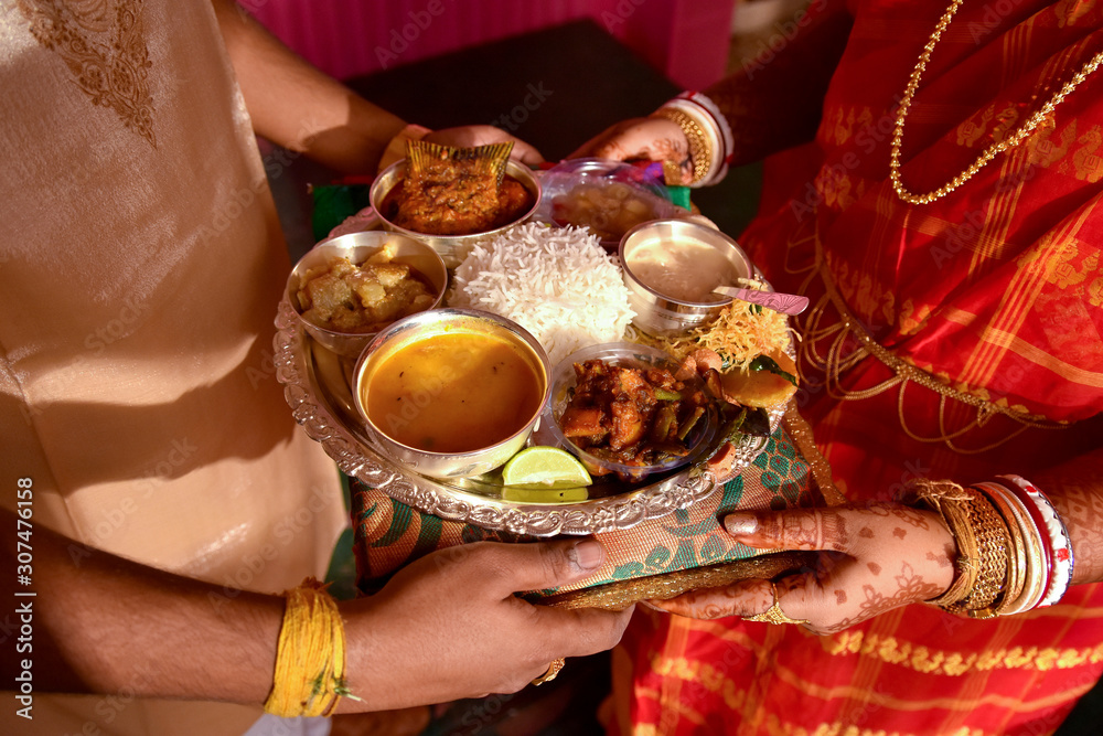 Fototapeta premium Newly married husband and wife exchanging Traditional Indian food Thali after marriage , A traditional Bengali wedding rituals in West Bengal or Bangladesh.