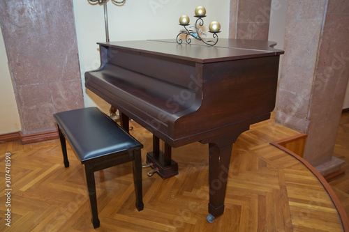 Old wooden piano keys on wooden musical instrument in front view . Big brown wooden piano close up in room .