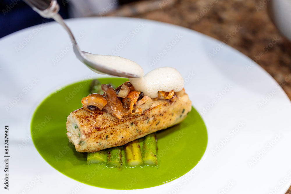 Closeup shot of grilled fish and fried asparagus in a green vegetarian sauce
