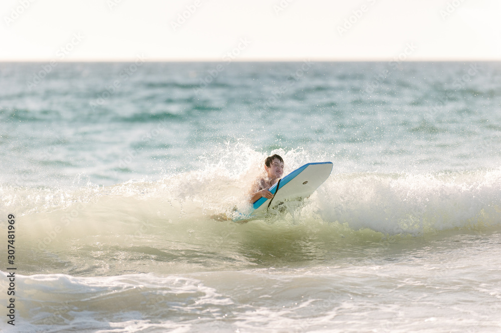 Boy catching a wave on a small boogie board at the beach Boy catching a wave on a small boogie board at the beach