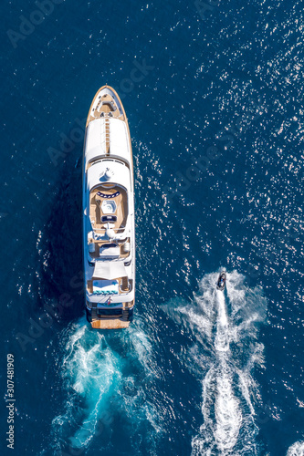 Vertical high angle shot of a private yacht and a small motorboat sailing in the ocean