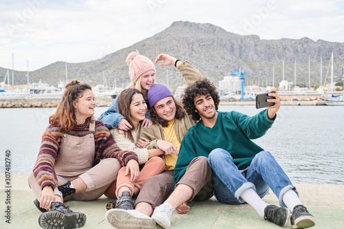 Friends on pier of lake and taking photo.