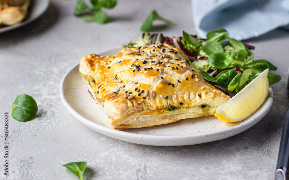 Puff pastry pie with salmon, spinach and ricotta cheese served with green lettuce leaves. Salmon Wellington in puff pastry. Puff pastry pie with salmon, spinach and ricotta cheese served with green lettuce leaves. Salmon Wellington in puff pastry.
