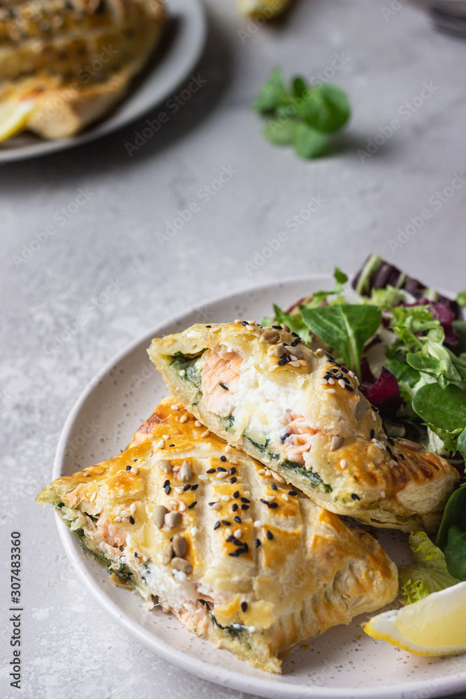 Puff pastry pie with salmon, spinach and ricotta cheese served with green lettuce leaves. Salmon Wellington in puff pastry. Puff pastry pie with salmon, spinach and ricotta cheese served with green lettuce leaves. Salmon Wellington in puff pastry.