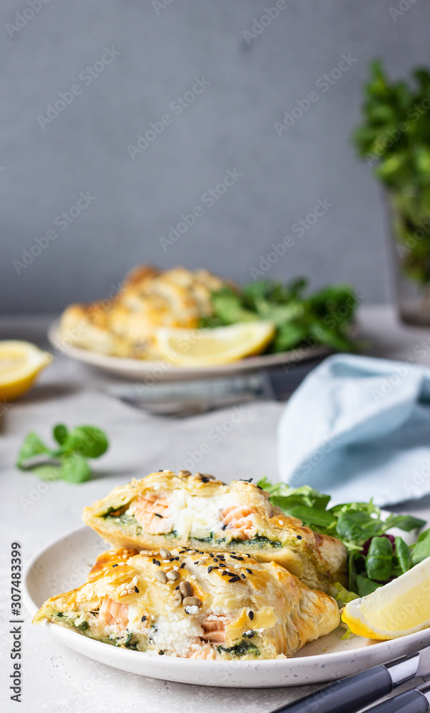 Puff pastry pie with salmon, spinach and ricotta cheese served with green lettuce leaves. Salmon Wellington in puff pastry. Puff pastry pie with salmon, spinach and ricotta cheese served with green lettuce leaves. Salmon Wellington in puff pastry.