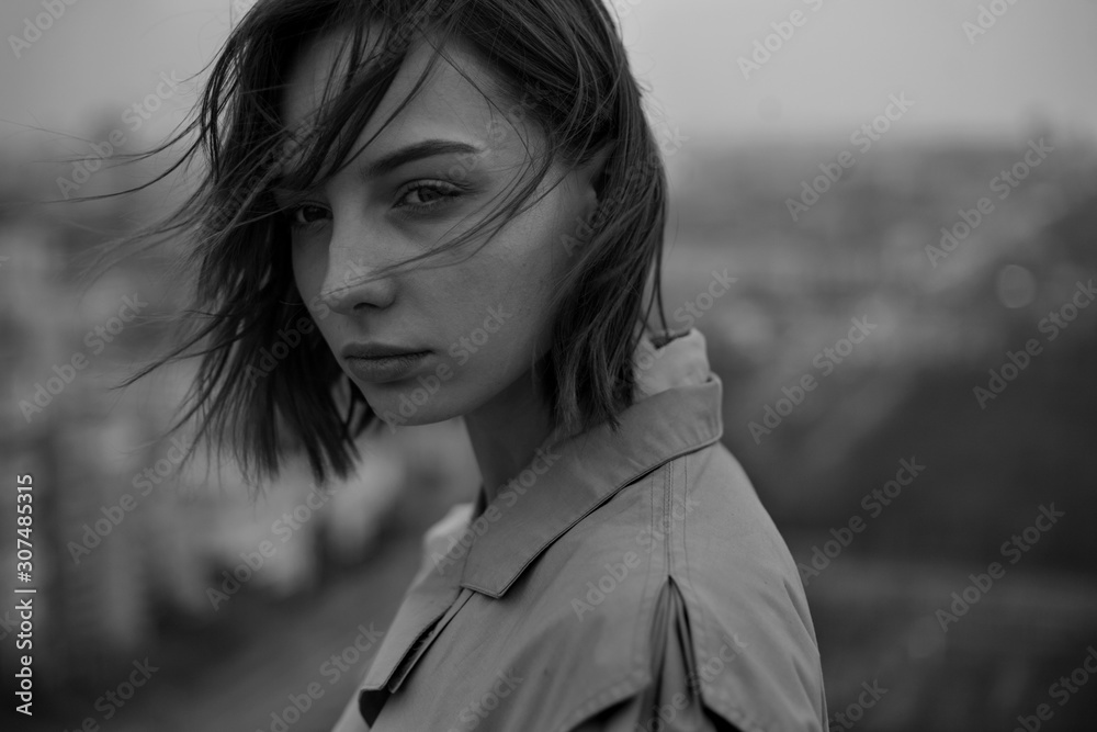 black-white portrait of a beautiful girl in a coat with developing against the background of the city black-white portrait of a beautiful girl in a coat with developing against the background of the city