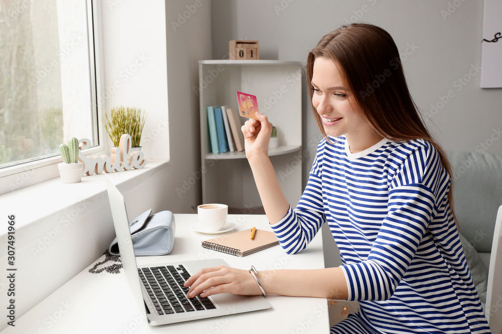 Young woman with credit card and computer shopping online at home Young woman with credit card and computer shopping online at home