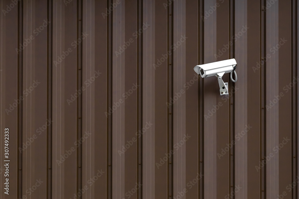 Building with Surveillance or Security Camera on metal brown wall, corrugated texture, galvanized steel surface, Abstract architectural pattern for background with copy space