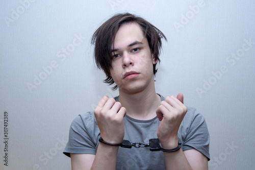 Obraz na plátne A handcuffed teenager sits on a grey background