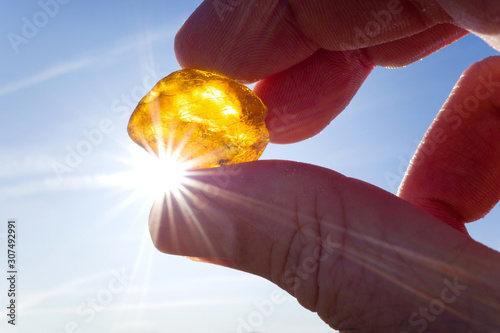 male hand holds amber against the sun photo