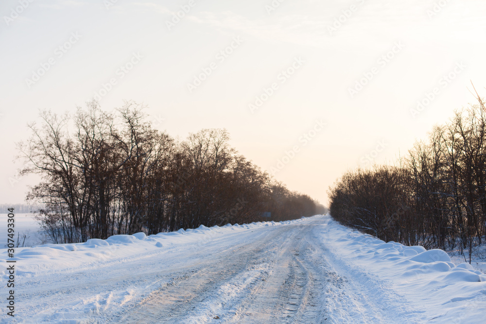 Winter poorly cleared road. Road in the countryside strewn with snow. Winter landscape with snowdrifts Winter poorly cleared road. Road in the countryside strewn with snow. Winter landscape with snowdrifts
