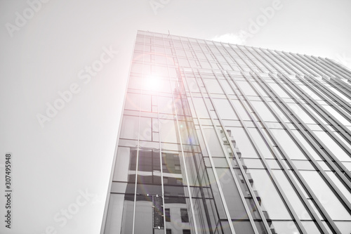 Modern office building wall made of steel and glass with blue sky. Glass surface with sunlight. Black and white.