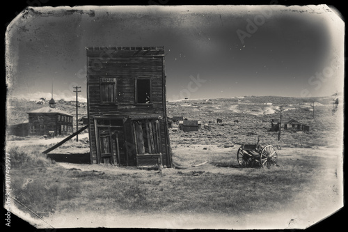 Photography Very old sepia vintage photo with abandoned and crooked western city building bu