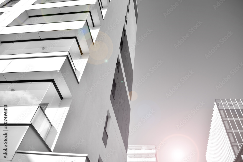 Obraz premium Detail of modern residential flat apartment building exterior. Fragment of new luxury house and home complex. Glass surface with sunlight. Black and white.