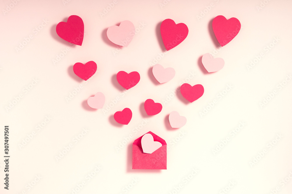 Valentine's day composition. Pink and red hearts blowing from envelope on pink background. Love message letter concept