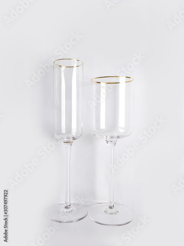 Two clean new transparent glasses with a gold rim for champagne or wine on a white background. Dishes for a party or celebration.