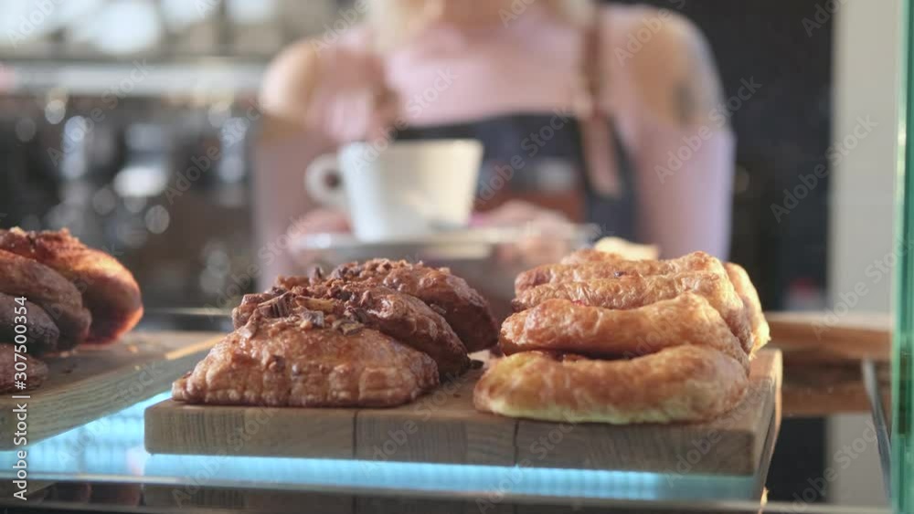 Fresh pastries in the confectionery store. The focus shifts from baking on a display case to a saleswoman standing at the counter Fresh pastries in the confectionery store. The focus shifts from baking on a display case to a saleswoman standing at the counter