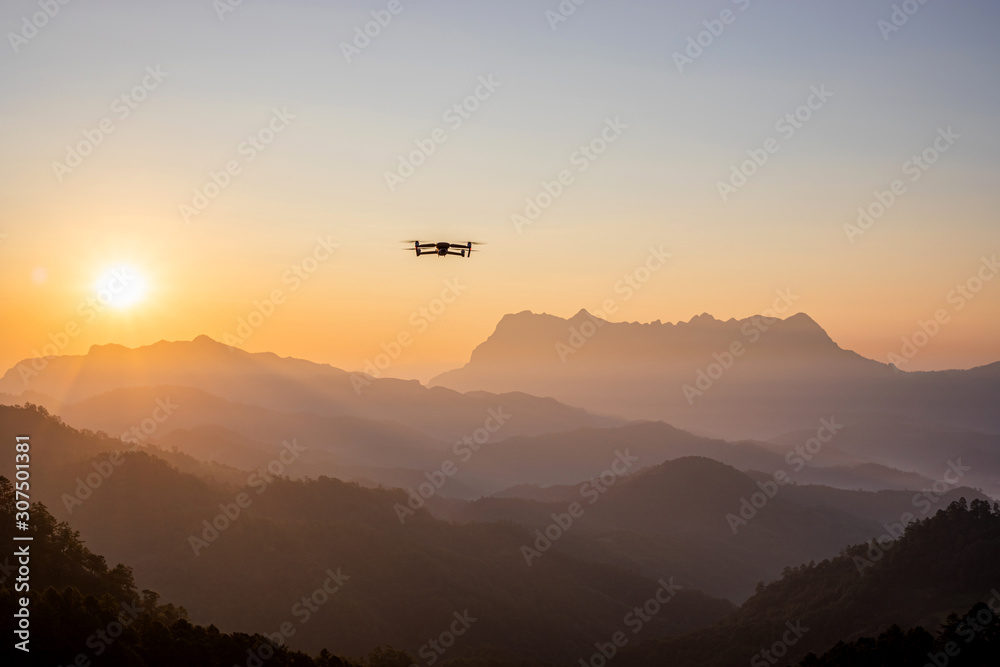 The drone with the professional camera takes pictures of the misty mountains at sunset. The drone with the professional camera takes pictures of the misty mountains at sunset.