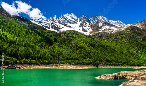 Green lake in Gran Paradiso Italian alps mountains in Graian Alps in Piedmont, Italy with snow capped peaks. © 365_visuals