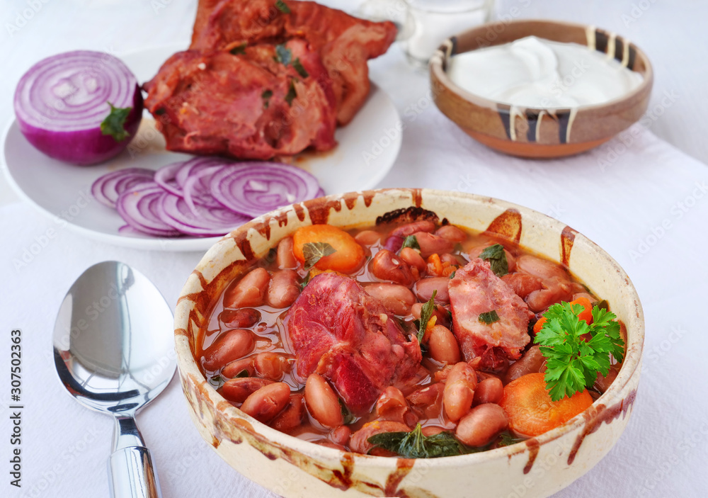Pinto bean soup and smoked ham hock in bowl served with sour cream and red onions Pinto bean soup and smoked ham hock in bowl served with sour cream and red onions