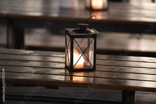 A lamp with a burning candle stands on a table of a restaurant without guests