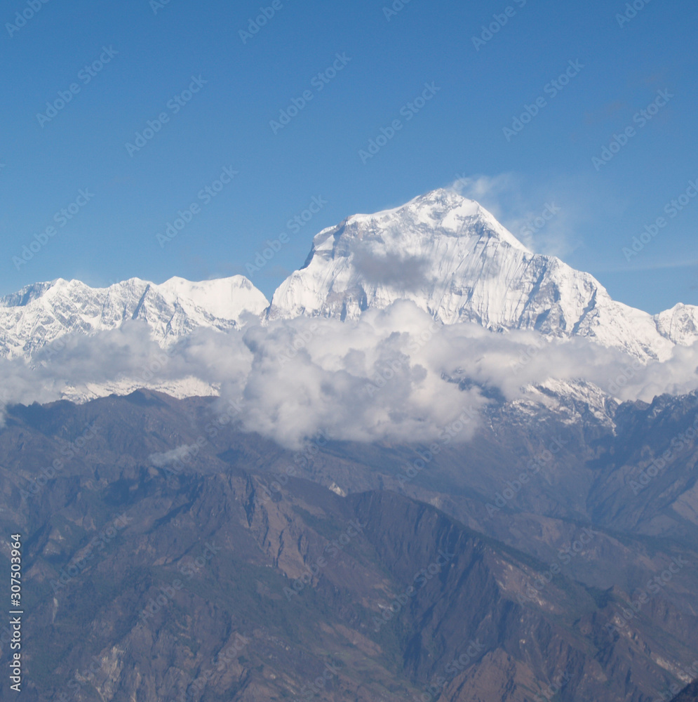 Amazing autumn panorama with mountains covered with snow and forest against the background of blue sky and clouds. Mount Everest, Nepal.