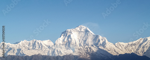 Mountain landscape panorama. Majestic mountain peaks covered with snow against a bright blue sky.