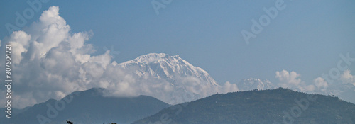 Manaslu mountain with snowy peaks in clouds on sunny bright day in Nepal.