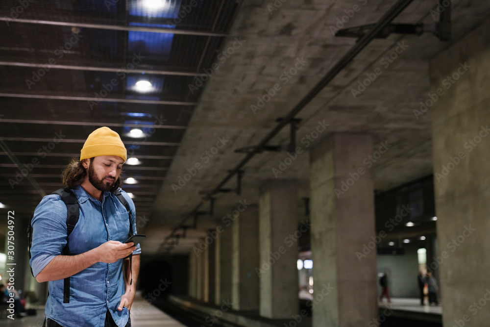 Man waiting at platform using smartphone, Berlin, Germany Man waiting at platform using smartphone, Berlin, Germany