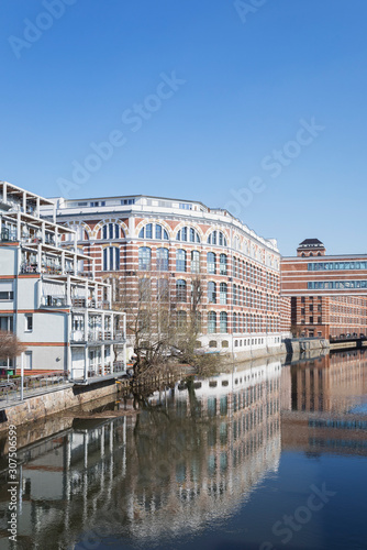 Buildings by White Elster against clear blue sky during sunny day in Saxony, Germany photo