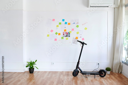 Electric scooter in front of a wall full of sticky notes in a bright modern office photo