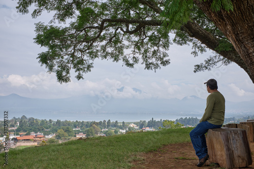 Hombre sentado viendo paisaje de lago de Patzcuaro desde zona arqueologica de Tzintzuntzan