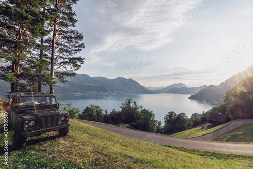 Switzerland, Gersau, Schwyz, 4x4 car parked along winding road with Lake Lucerne in background photo