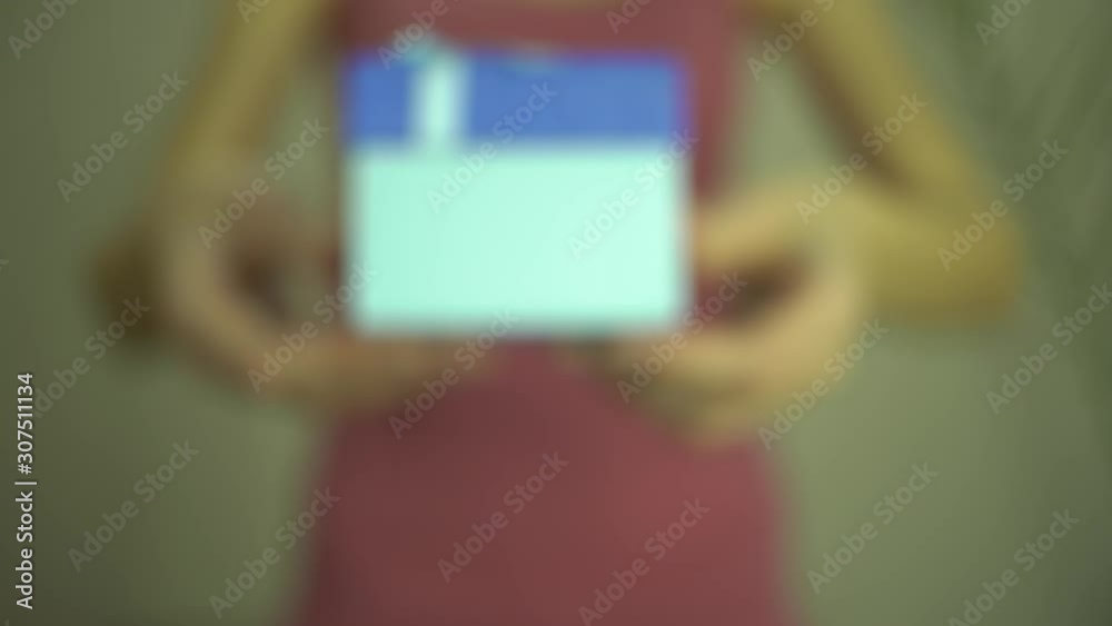 Valentine's Day. Christmas. Women's hands in defocusing hold out a gift in the form of a box with a ribbon on the camera.