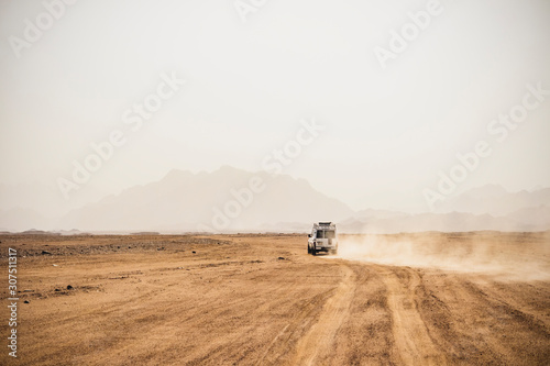 Off-road vehicle moving on arid landscape against clear sky during sunny day, Suez, Egypt photo