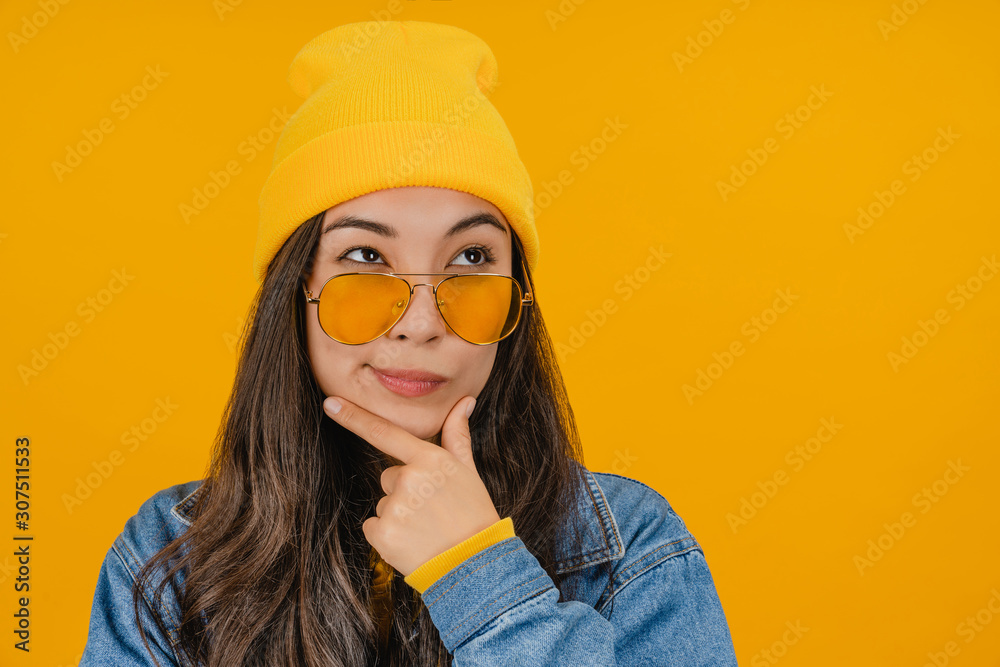 Close up portrait of cute thinking young woman posing isolated over yellow background Close up portrait of cute thinking young woman posing isolated over yellow background