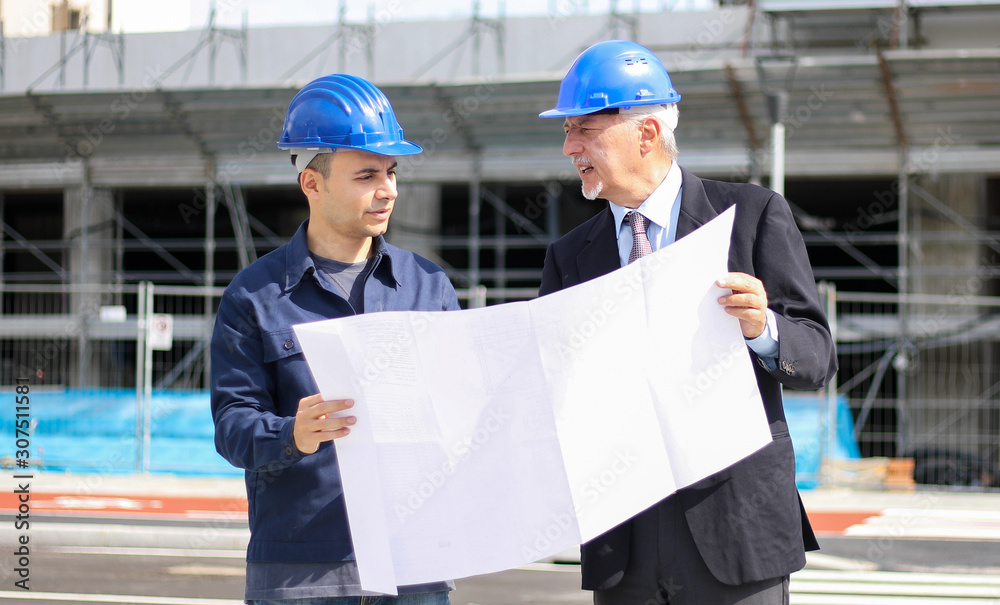 Two architect developers reviewing building plans at construction site Two architect developers reviewing building plans at construction site