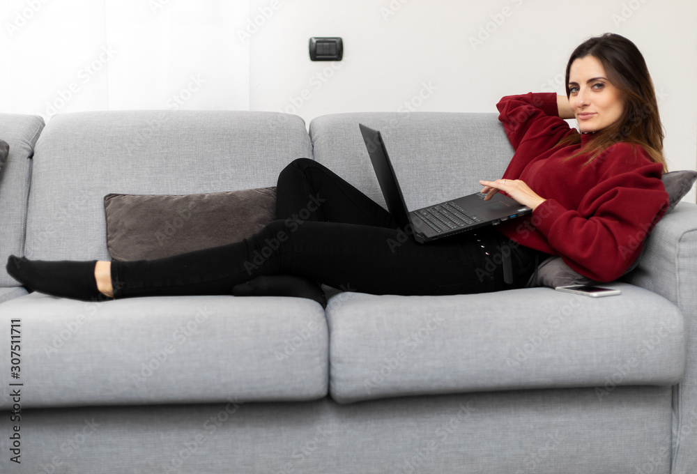 Woman using a laptop while relaxing on the couch Woman using a laptop while relaxing on the couch