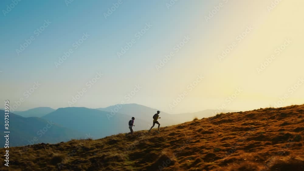 Aerial shot of a woman and a man running together in the hills