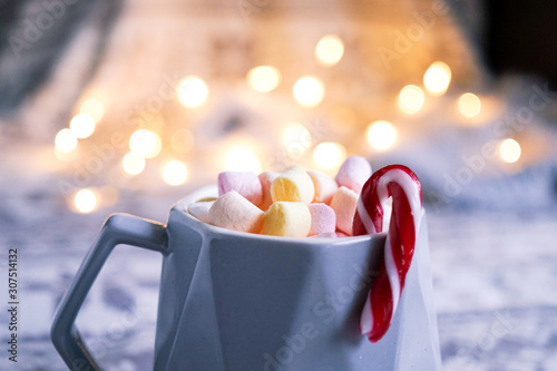 Cup of hot chocolate with marshmallows and candy cane. Lifestyle, christmas photo with bokeh