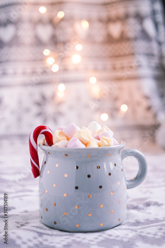 Cup of hot chocolate with marshmallows and candy cane. Lifestyle, christmas photo with bokeh